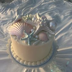 there is a cake decorated with seashells and pearls on the tablecloth,