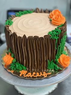 a cake with frosting and orange flowers on it sitting on top of a table