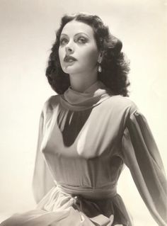 a black and white photo of a woman in a dress with her hands on her hips