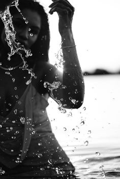 a woman standing in the water holding her arm up