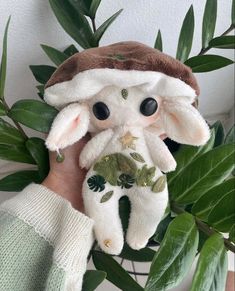 a person holding a stuffed animal in front of a plant