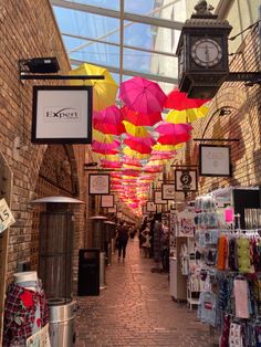 an indoor market with many colorful umbrellas hanging from it's ceiling and people walking down the walkway