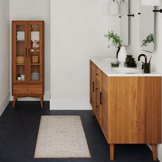 a bathroom with a wooden cabinet, sink and rug on the floor next to it