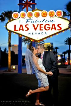 a bride and groom kissing in front of the las vegas sign