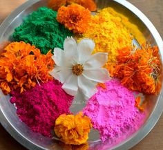 colorful powder and flowers in a bowl on a wooden table, with the petals still attached