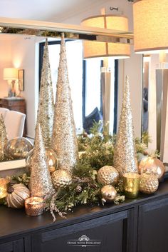 christmas decorations are displayed on a table in front of a mirror and candlesticks