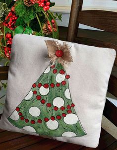 a green christmas tree pillow sitting on top of a wooden chair