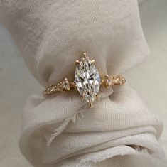 a diamond ring sitting on top of a white cloth with a knot around it's edge