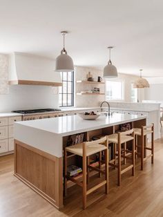 a large kitchen with an island in the middle and two pendant lights hanging over it