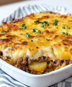 a casserole dish with meat and cheese in it on a blue and white towel