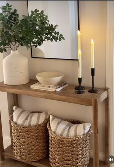 a wooden table topped with two baskets next to a candle