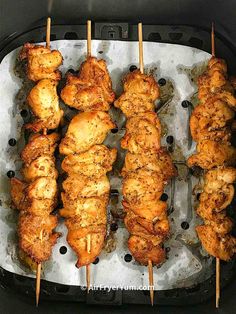 chicken skewers are being cooked in an air fryer with toothpicks