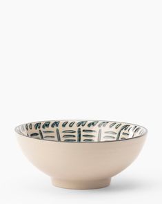 a white and blue bowl with designs on the rim, sitting in front of a white background