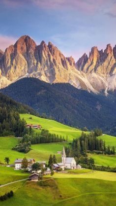 the mountains are covered in green grass and trees, while houses sit on top of them