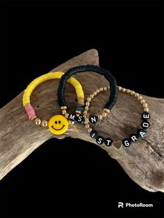 three bracelets with smiley faces and words on them