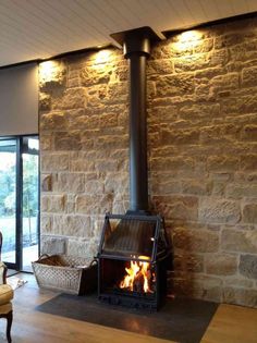 a living room filled with furniture and a fire place next to a stone wall covered in lights