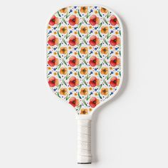 an orange and yellow flower pattern on a white paddle with black handle, against a white background