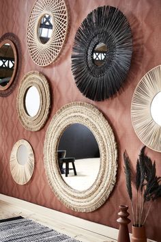 the wall is decorated with round mirrors and vases on it, along with other decorative items