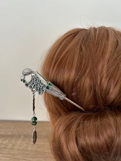 Channel your inner goddess with this enchanting peacock hair stick. 🌺🦚 Its emeral green hues, intricate feather details, and hanging feather tassel. A mesmerizing hair accessory that will turn heads. Peacock hair stick Peacock Feather Hair Stick, Emerald Green Hair Stick, Feather Hair Pin Peacock Hair Jewelry or can be used as a bookmark.  Antique Silver in color with Green Rhinestones and 8mm glass crystal beads. Approximate Length 17cm x 2.8cm. The peacock is one sided but the backing metal Peacock Bookmark, Emerald Green Hair, Peacock Hair, Peacock Jewelry, Feather Hair, Flower Hair Comb, Bun Hair, Feather Jewelry, Bun Hairstyles For Long Hair