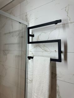 two towel racks in a bathroom next to a glass shower door and marble tile wall