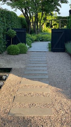 an outdoor walkway with steps leading to trees and bushes in the background, surrounded by gravel