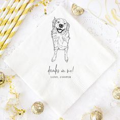 a white napkin with a black dog on it next to some gold and white straws