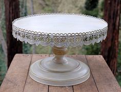 a white cake plate sitting on top of a wooden table