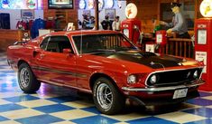 a red car parked inside of a garage next to a checkered blue and white floor