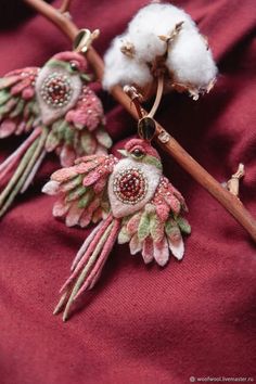 two pieces of fabric are hanging from a twig with some cotton on it and one piece has been made to look like flowers