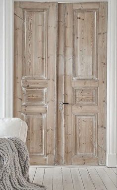 an empty room with two wooden doors and a white couch in front of the door