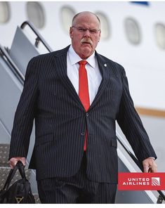 a man in a suit and tie walking down an escalator at an airport