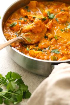 a pan filled with chicken curry and garnished with cilantro on the side