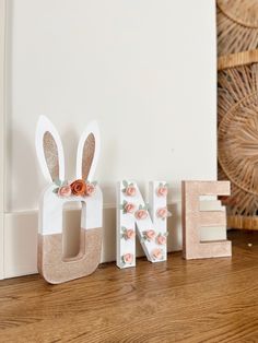 the letters are made out of wood and have flowers on them, along with a bunny's head