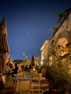 an outdoor dining area at night with tables and umbrellas set up outside on the patio