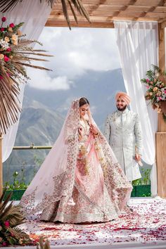 the bride and groom are walking down the aisle at their wedding ceremony in front of an arch decorated with flowers