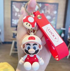 a hand holding a nintendo keychain with a mario on it