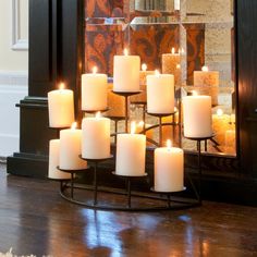 a large group of white candles sitting on top of a table next to a mirror