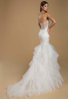 a woman in a white wedding dress standing on a beige background with her back to the camera