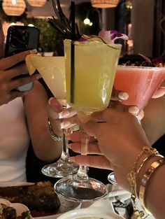 three people holding up drinks at a table with food and drink glasses in front of them