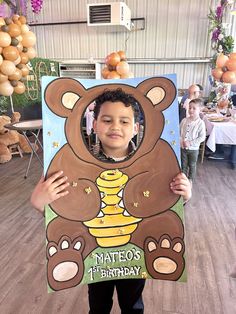 a young boy holding up a teddy bear cutout in front of his face with the words mateos 1st birthday on it