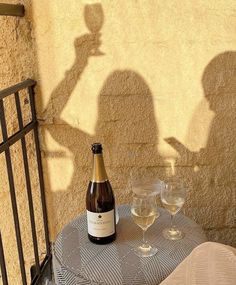 a bottle of wine sitting on top of a table next to two glasses of wine