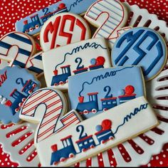 decorated cookies are arranged on a plate with red, white and blue decorations in the shape of trains