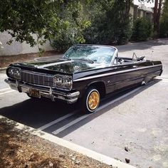 an old black car parked in a parking lot