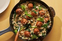 a skillet filled with pasta and meatballs on top of a yellow tablecloth