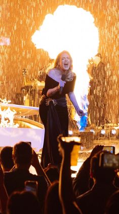 a woman standing on top of a stage in front of a crowd