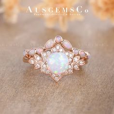 an opal and diamond ring on a wooden surface with flowers in the background at ausgems co