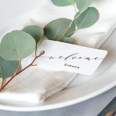 a white plate topped with green leaves and a name tag