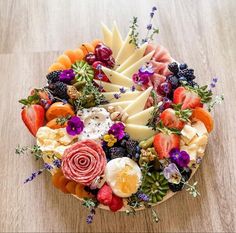 an assortment of fruits and cheeses arranged in a circular arrangement on a wooden table