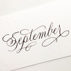 some type of calligraphy that is written in black ink on white paper with the word september