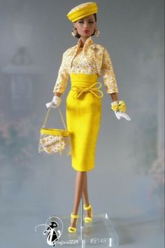 a barbie doll wearing a yellow dress and hat with matching purses in her hand